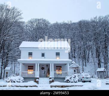 Historic 1868 John L. Bullard house set among the trees covered with freshly fallen snow with a Christmas tree on the front porch in winter. Stock Photo