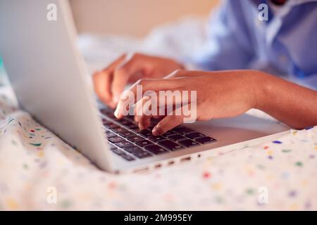 Close Up Of Boy In Bedroom Typing On Keyboard Of Laptop Stock Photo
