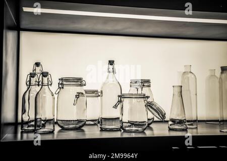 A display of glass objects: group of bottles and jars in black and white Stock Photo