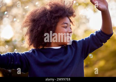 Smiling Boy Outdoors Having Fun Playing With Bubbles In Garden Stock Photo