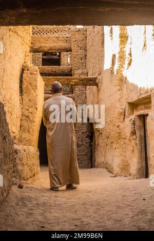 DAKHLA, EGYPT - FEBRUARY 8, 2019: Local man walking in a narrow street in Al Qasr village in Dakhla oasis, Egypt Stock Photo