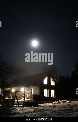 Landscape with house at night under dark sky with full moon. Spooky landscape with house in night. Stock Photo