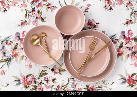 Crockery and cutlery on a white tablecloth with floral pattern, table top view, above. Flat lay design. Ceramic empty plates, utensils for serving. Tr Stock Photo