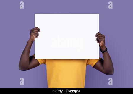 Black man hiding behind empty advert board Stock Photo