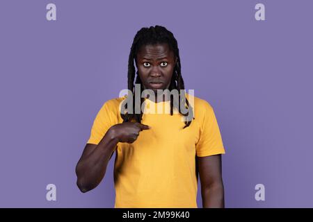 Surprised long-haired black guy pointing at himself, purple background Stock Photo