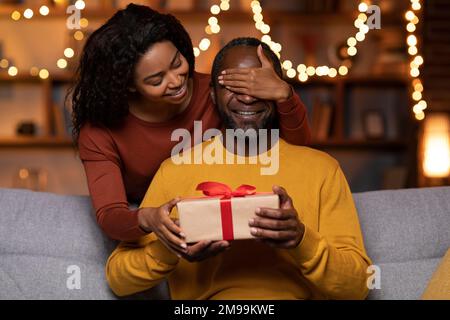 Loving african american woman making birthday surprise for husband Stock Photo
