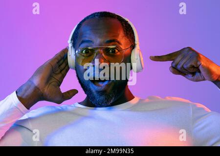 Amazed black man wearing sunglasses using wireless headphones Stock Photo
