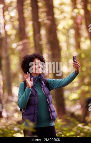 Woman On Hike Through Forest Having Video Call On Mobile Phone Stock Photo