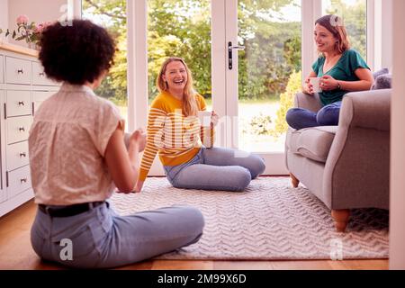 Group Of Female Friends Relaxing At Home Sitting On Sofa Chatting And Drinking Coffee Together Stock Photo