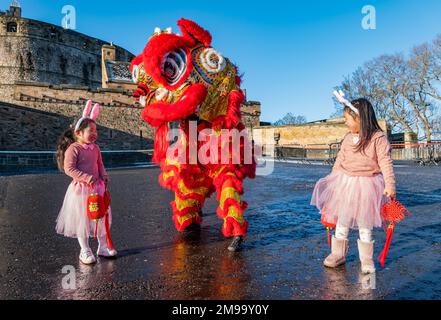 Young Chinese girls wearing rabbit ears entertained by dragon dancers to celebrate Chinese New Year, (Year of rabbit), Edinburgh Castle, Scotland, UK Stock Photo