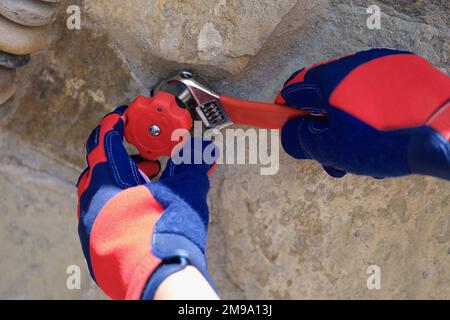 Handyman in gloves with wrench fixing water pipes oudoor. Stock Photo