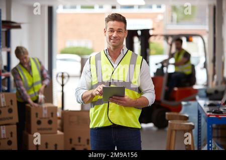 Portrait Of Male Worker In Logistics Distribution Warehouse Using Digital Tablet Stock Photo