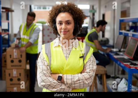 Portrait Of Female Worker Using Headset In Distribution Warehouse Stock Photo