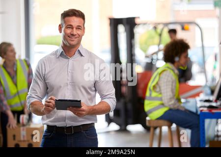Male Manager In Logistics Distribution Warehouse Using Digital Tablet Stock Photo