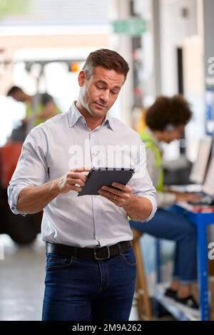 Male Manager In Logistics Distribution Warehouse Using Digital Tablet Stock Photo