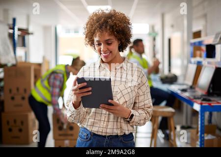 Female Manager In Logistics Distribution Warehouse Using Digital Tablet Stock Photo