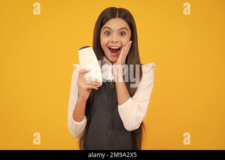 Amazed teen girl. Teenage girl with shampoos conditioners or shower gel. Kids hair care cosmetic product, shampoo bottle. Excited expression, cheerful Stock Photo