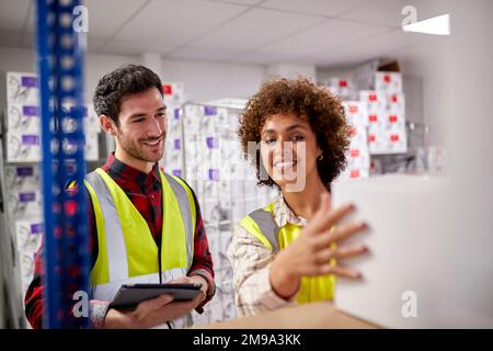 Male And Female Workers In Logistics Distribution Warehouse Using Digital Tablet Stock Photo