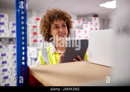 Female Worker In Logistics Distribution Warehouse Using Digital Tablet Stock Photo