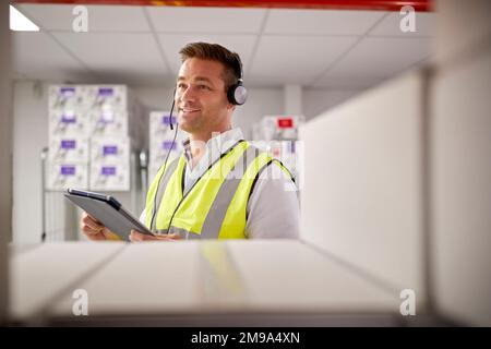 Male Worker Wearing Headset In Logistics Distribution Warehouse With Digital Tablet Stock Photo
