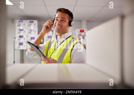 Male Worker Wearing Headset In Logistics Distribution Warehouse With Digital Tablet Stock Photo