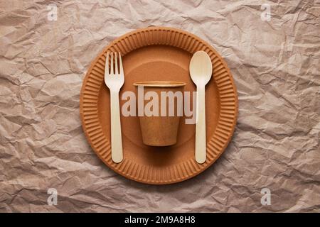 Wooden fork, spoon on cardboard plate on crumpled paper background Stock Photo