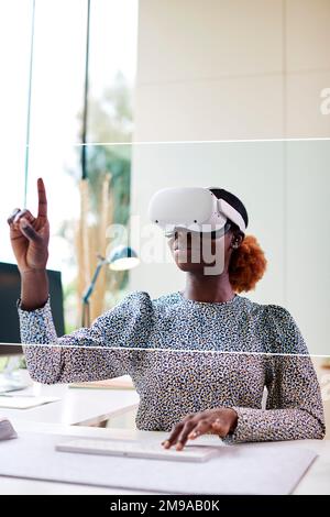 Woman Working From Home Office Sitting At Desk Wearing VR Headset Interacting With AR Technology Stock Photo