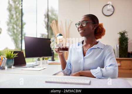 Woman Working From Home Office Sitting At Desk Drinking Coffee Stock Photo