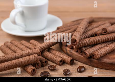 Tray with tasty rolled wafer cookies, coffee beans and cup on wooden background Stock Photo