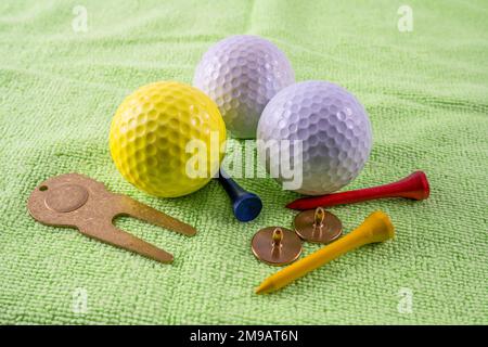 golf accessory essentials high quality ball markers and divet repairer with balls and tees on a putting practice mat indoors Stock Photo
