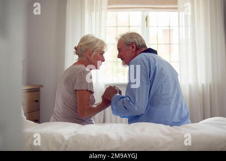 Worried Retired Senior Couple Sitting On Bed At Home Together Stock Photo