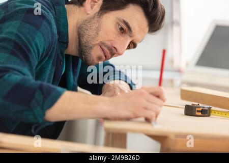 a carpenter marking a hole in a furniture part Stock Photo