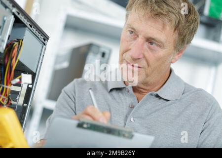 engineering holding clipboard next to pc Stock Photo