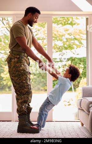 Loving Army Father In Uniform Home On Leave With Son Standing On Feet And Holding Hands Stock Photo