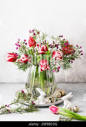 Still life with pink, white tulips and purple wax flower flowers in the old vintage glass vase. Homemade decoration for Eastern Stock Photo