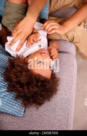 Father Tickling Son Making Him Laugh Lying On Sofa At Home Stock Photo