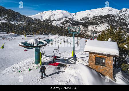 People, skiers taking off from chair ski lift with snowy mountains and forest in a background. Winter holidays in El Tarter, Andorra Pyrenees Mountain Stock Photo