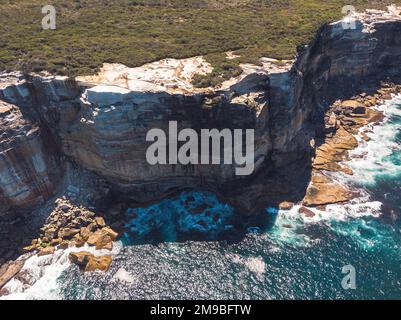 A scenic aerial top view of ocean waves hitting the rocky cliff at Wedding Cake Rock beach in Sydney Stock Photo