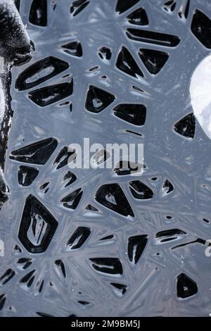 Tryptophobic shapes on a water surface that has sunk as it freezes Stock Photo