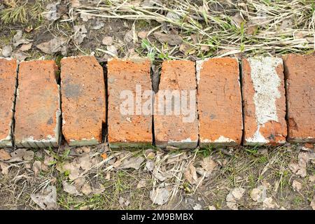 Bricks on ground. Old bricks lie in row. Stones are stacked together. Background is made of stone. Stock Photo