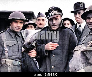 Werner Voigt (centre in large coat), a captured German pilot, who had crashed his Messerschmitt 109 into the sea off Dover, seen with British soldiers, Summer 1940. Stock Photo