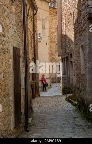 Woman standing in an ally in Casso (Cas in local dialect, Sćjas in Friulan) Italy. Stock Photo