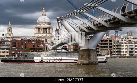 A boat passing under the Millennium bridge in London with the Saint Paul cathedral in the background Stock Photo