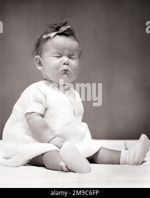 1940s BABY GIRL SITTING UP WEARING DRESS BOW IN HER HAIR A NECKLACE POUTING EYES CLOSED ABOUT TO CRY BAD TASTE OR SOUR TASTE - b17869 HAR001 HARS FACIAL ANGER FEAR COMMUNICATION COMIC INFANT WORRY LIFESTYLE FEMALES STUDIO SHOT MOODY TEARS HOME LIFE COPY SPACE FULL-LENGTH CRY EXPRESSIONS TROUBLED B&W CONCERNED SADNESS HUMOROUS WEEPING POUTING BOOTIES COMICAL TASTE BAWLING UP MOOD SOBBING FUNNY FACE GLUM COMEDY OR SCRUNCHING BAD TASTE JUVENILES MISERABLE SCRUNCHED SOUR BABY GIRL BLACK AND WHITE CAUCASIAN ETHNICITY EYES CLOSED HAR001 OLD FASHIONED SITTING UP Stock Photo