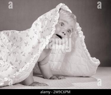 1960s BABY CRAWLING AND PEEKING OUT FROM UNDER A BLANKET - b22624 HAR001 HARS WONDER HEAD AND SHOULDERS PEOPLE BABIES WONDERMENT CURIOUS JUVENILES LOOKING UP BABY GIRL BLACK AND WHITE BLUE EYED BLUE EYES CAUCASIAN ETHNICITY HAR001 OLD FASHIONED Stock Photo