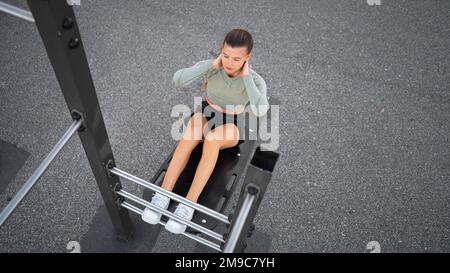 Sit-ups exercises. Active, fit sporty woman doing situps, exercising and training on fitness outdoor gym. One young, serious and athletic female exercising, working out doing physical activity. Banner Stock Photo