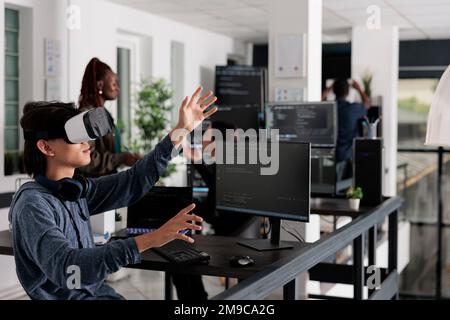 Asian programmer working with virtual reality glasses in it big data office, using vr headset to develop security program. Web developer coding html script with database on computer Stock Photo