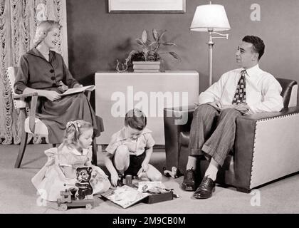 1950s FATHER MOTHER SITTING TOGETHER WITH SON DAUGHTER PLAYING ON RUG IN LIVING ROOM FURNISHED IN MID-CENTURY MODERN STYLE - j171 HAR001 HARS INDOORS NOSTALGIC PAIR 4 SUBURBAN URBAN MOTHERS OLD TIME NOSTALGIA BROTHER OLD FASHION SISTER 1 JUVENILE COMMUNICATION SECURITY RUG FAMILIES JOY LIFESTYLE SATISFACTION CELEBRATION FEMALES MARRIED BROTHERS SPOUSE HUSBANDS MODERN HOME LIFE FULL-LENGTH LADIES PERSONS INSPIRATION CARING MALES SERENITY SIBLINGS CONFIDENCE SISTERS FATHERS B&W PARTNER SUCCESS WIDE ANGLE DREAMS HAPPINESS LEISURE STRENGTH LIVING ROOM CHOICE DADS RECREATION INNOVATION PRIDE IN ON Stock Photo