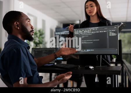 App developers working on temrinal window with html script and writing server code on computer, sitting in big data room. System engineer programming user interface in busy developing agency. Stock Photo