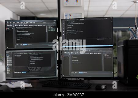 Computer monitors on desk compiling programming html data algorithms in empty software company. Database network servers cloud computing in it agency room, code script language. Stock Photo